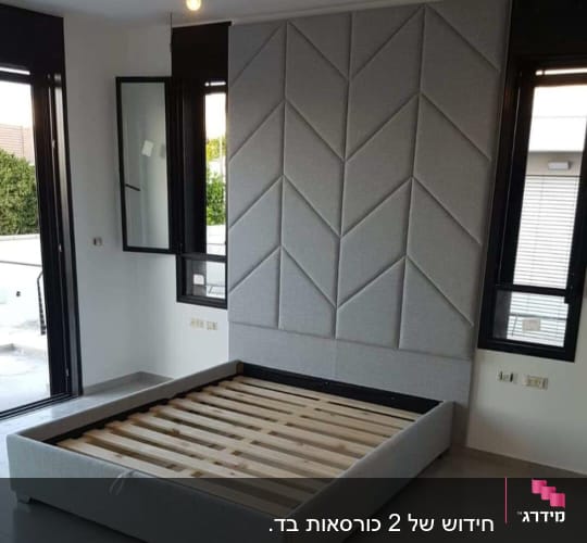 מיטה עם ריפוד אפור על קיר